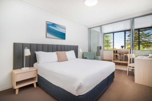 a bedroom with a large bed and a desk and a chair at Mantra The Observatory in Port Macquarie