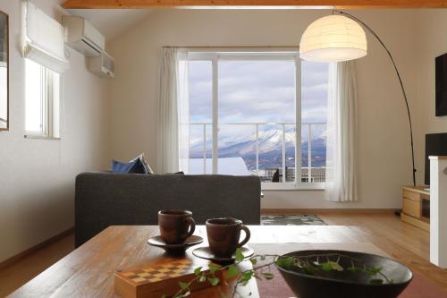 een woonkamer met een tafel en een groot raam bij Wonderland Furano Maple in Furano