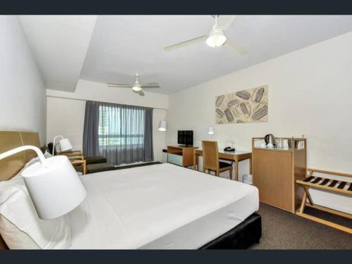 1 dormitorio con 1 cama blanca grande y escritorio en Executive Studio Darwin CBD (Water Views) en Darwin