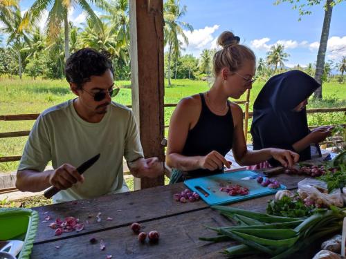 a group of people standing around a table preparing food at Sunset Homestay by Harry & Mimin in Telaga