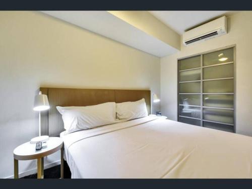 a bedroom with a large white bed and a table at Pandanas Apt 3 (Darwin CBD, Harbour views) in Darwin