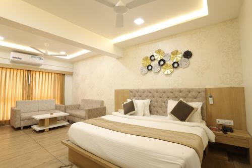a hotel room with a large bed and a chair at Hotel Lotus in Anand