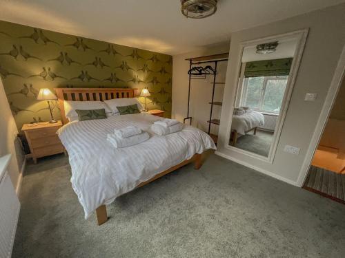 ein Schlafzimmer mit einem großen Bett und einem Spiegel in der Unterkunft Knodishall - Newly renovated 2 bed holiday home, near Aldeburgh, Leiston and Thorpeness in Aldringham