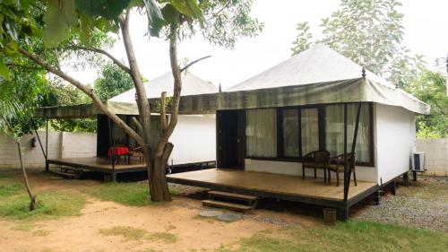 a small white house with a porch and a tree at 16 Bedouin Private Pool Villa in Hosūr