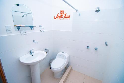 een witte badkamer met een toilet en een wastafel bij Hotel Leito Inn in Tarapoto