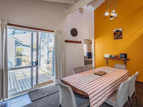 a dining room with a table and a balcony at Ariki - National Park Holiday Home in National Park