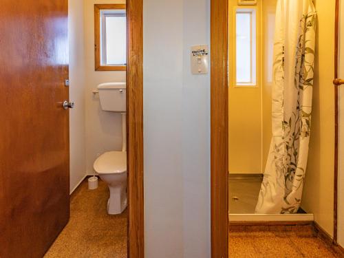 a bathroom with a toilet and a window and a door at Ariki - National Park Holiday Home in National Park