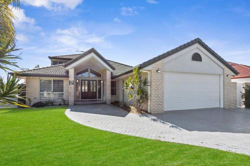 a house with a garage and a green lawn at Voyagers Resort - Stunning home! in Banksia Beach