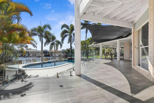 an outdoor patio with a pool and palm trees at Voyagers Resort - Stunning home! in Banksia Beach