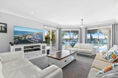 a living room with white furniture and a flat screen tv at Voyagers Resort - Stunning home! in Banksia Beach
