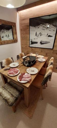 une table en bois avec des assiettes de nourriture dessus dans l'établissement 40m2 - Ski aux pieds - La Tania - Parking couvert, à La Tania