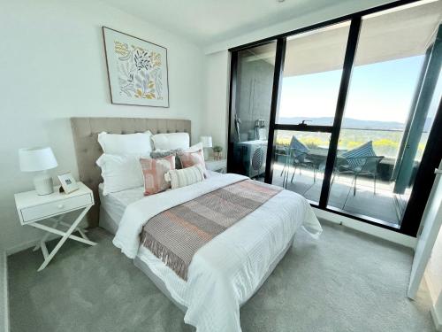 a bedroom with a bed and a large window at Rest Skygarden Collection in Glen Waverley