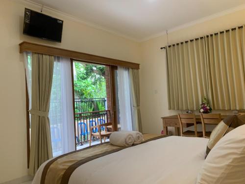 a bedroom with a bed and a large window at Betesda Guest House in Canggu