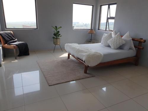 a bedroom with a bed and a chair and windows at Mohau Accommodation in Elandsfontein
