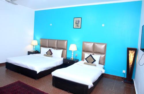 2 łóżka w pokoju z niebieską ścianą w obiekcie Premier inn Mall Lahore w mieście Lahaur