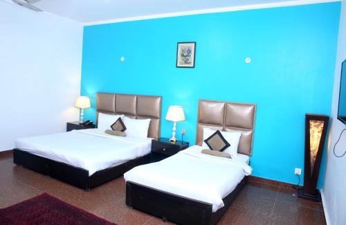 two beds in a room with a blue wall at Premier inn Mall Lahore in Lahore