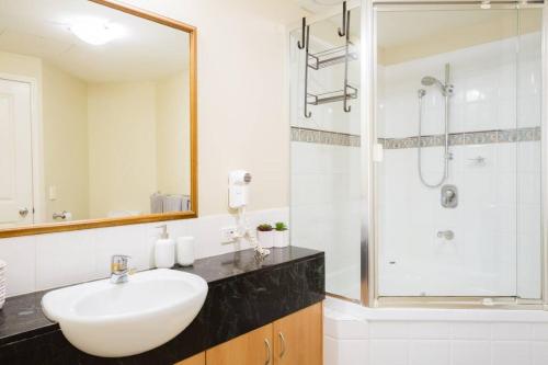 a white bathroom with a sink and a shower at Gem in the Heart of Mooloolaba - Landmark Resort in Mooloolaba