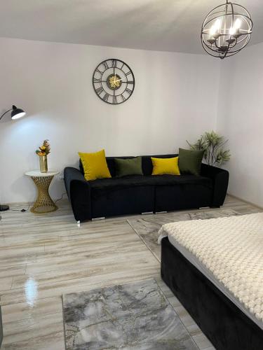 ein Wohnzimmer mit einem schwarzen Sofa und einer Uhr an der Wand in der Unterkunft Garsoniera Maria in Alba Iulia