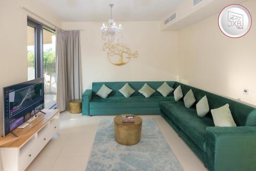 a living room with a green couch and a tv at 5 bedroom Villa - Dubai Hills in Dubai