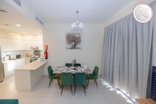 5 bedroom Villa - Dubai Hills في دبي: مطبخ وغرفة طعام مع طاولة وكراسي خضراء