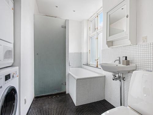 Sanders Stage - Enchanting Four-Bedroom Apartment Near Nyhavn في كوبنهاغن: حمام مع مغسلة وغسالة ملابس