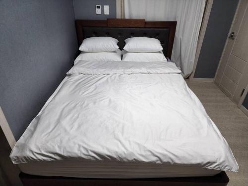 Una cama con sábanas blancas y almohadas. en Goeunjeong en Gwangju