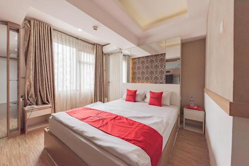 a bedroom with a large bed with red pillows at RedDoorz Apartment @ Jarrdin Cihampelas in Bandung
