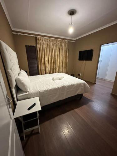 a hotel room with a bed and a television at Townhouse on 6526 Boiketlo Street, Golfview in Mahikeng