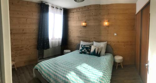 ein Schlafzimmer mit einem Bett mit einer Holzwand in der Unterkunft Les Marmottes 2 in Orcières