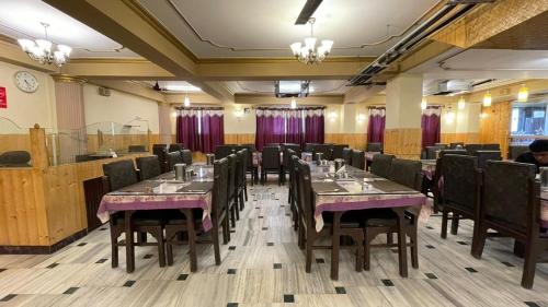 a restaurant with tables and chairs in a room at Hotel New Mamta in Srinagar