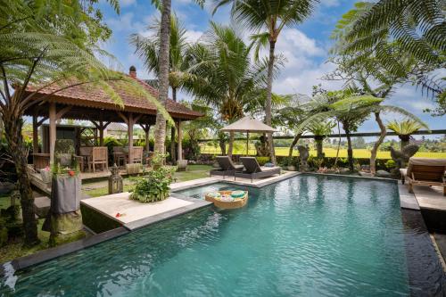 uma piscina num resort com palmeiras em Prabhu Ubud Villa em Ubud