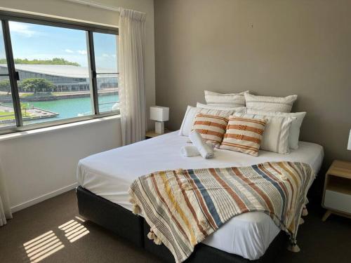 een slaapkamer met een groot bed en een groot raam bij Luxury Waterfront Stay 1bdr (breathtaking Views) in Darwin