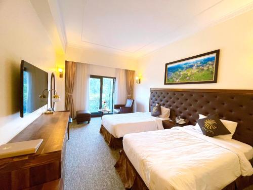 a hotel room with two beds and a desk at Phoenix Hotel Hà Giang in Ha Giang