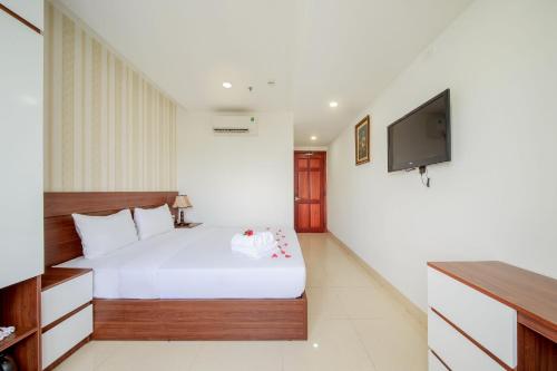 a bedroom with a white bed and a flat screen tv at Ha Nhung Hotel Nha Trang in Nha Trang