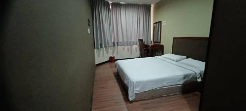 a bedroom with a white bed and a window at Hotel Sadong88 in Kota Kinabalu