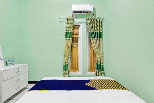 1 dormitorio con 1 cama con cortinas en la pared en SPOT ON 92012 Homestay Grand Mahkota Permai Syariah, en Cilacap