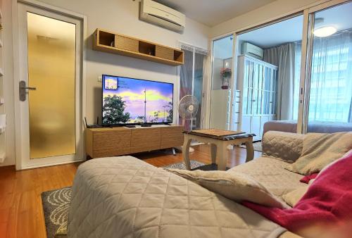 sala de estar con sofá y TV de pantalla plana en Rama9 Cozy Apartment, en Bangkok