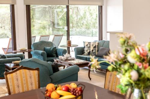 una sala de estar con sillas y una mesa con un bol de fruta en Platres Forty Pine Trees Cottage en Platres
