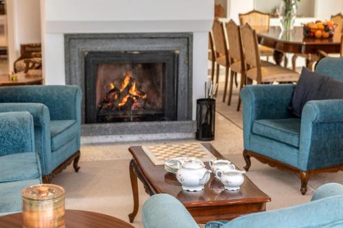 a living room with a fireplace with chairs and a table at Platres Forty Pine Trees Cottage in Platres