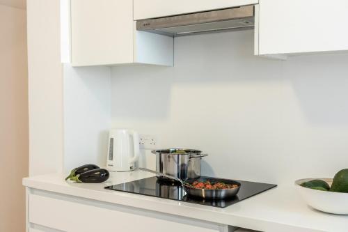 a kitchen with white cabinets and a stove top oven at Platres Forty Pine Trees Cottage in Platres