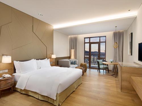 a bedroom with a large white bed and a living room at Holiday Inn Resort Zhangjiakou Chongli, an IHG Hotel in Chongli