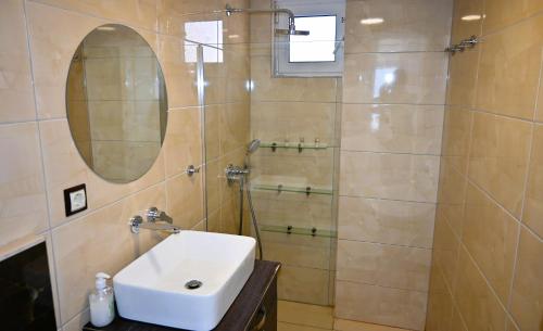 a bathroom with a sink and a shower with a mirror at Efi's Luxury Suite in Agios Nikolaos