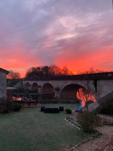 a bridge with a sunset in the background at Boutique B&B- The Riverside Retreat in Jarnac