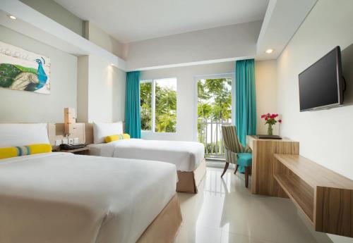 a hotel room with two beds and a television at Swiss-Belcourt Bogor in Bogor