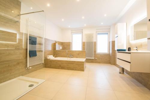ein großes Bad mit einer Badewanne und einem Waschbecken in der Unterkunft Luxury Saarbrücken 4 in Saarbrücken
