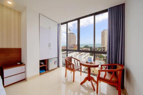 a bedroom with a table and chairs and a large window at Ha Nhung Hotel Nha Trang in Nha Trang