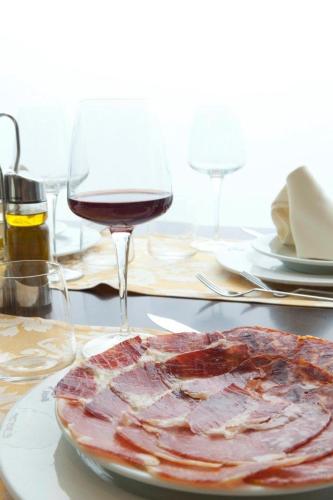 a plate of meat and a glass of wine on a table at Complejo Leo 24H in Monesterio