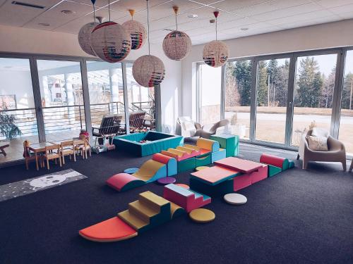 a living room with colorful furniture and large windows at Pohorje Village Wellbeing Resort - Family Apartments Bolfenk in Pohorje