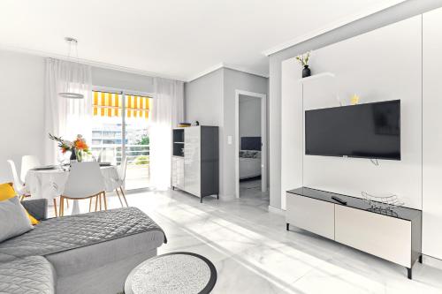 ein weißes Wohnzimmer mit einem Sofa und einem TV in der Unterkunft lovely sunny apartment with shared pool and private parking in Torrevieja