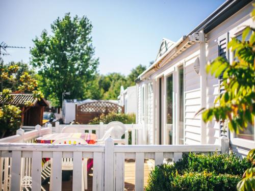 a porch with a white fence and a table and chairs at Camping Les Jardins de la Mer in Merlimont